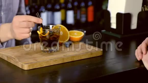 酒保把鸡尾酒放在酒杯上交给吧台的客人手特写视频的预览图