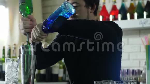 专业酒吧工作人员将带细颈的瓶子中的彩色液体倒入金属摇瓶中视频的预览图