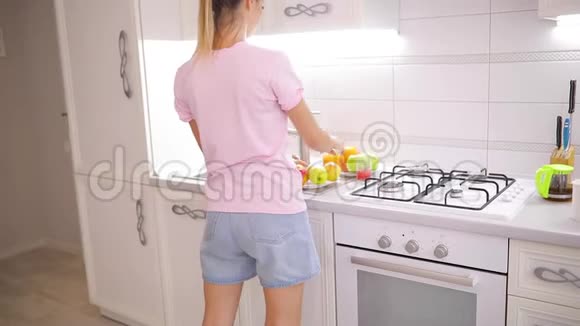 一个无忧无虑的周末早晨女人在家里的厨房里摆弄苹果视频的预览图