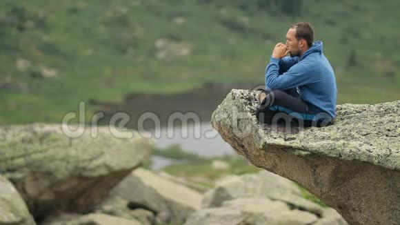 一个年轻人坐在悬崖边上吹口琴视频的预览图