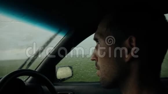 年轻的胡子男人开车在雨中开车视频的预览图