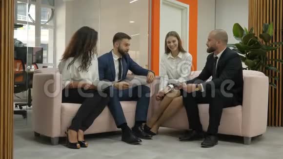 办公室工作人员两名青年男子和两名青年妇女站在一起讨论公司的一个重要项目男子握手视频的预览图