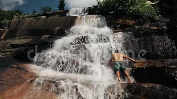 年轻的勇士在美丽的山瀑布里洗澡视频的预览图