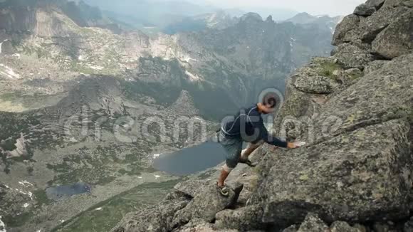 一个勇敢的年轻男性登山者在岩石上攀爬视频的预览图