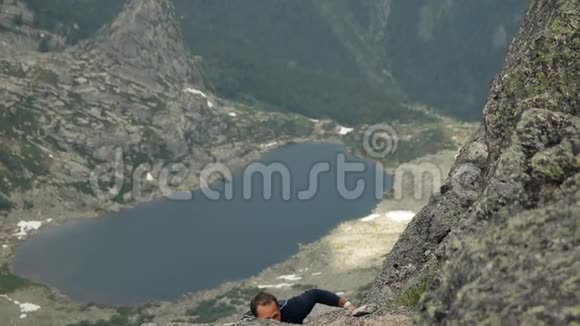 一个人爬上山湖背景上的岩石视频的预览图