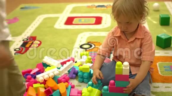 快乐的学龄前幼儿在室内操场上玩多种颜色的积木幼儿园教育视频的预览图