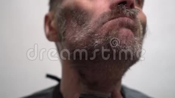 大胡子帅哥在镜子前用电动剃须刀刮胡子视频的预览图