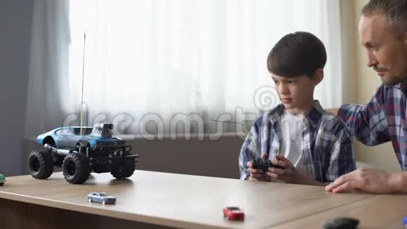 可爱的孩子和他的父亲在家经营无线电控制汽车技术视频的预览图
