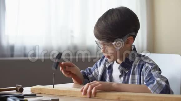 可爱的小男孩用木板钉钉子爱好和闲暇时间车间视频的预览图