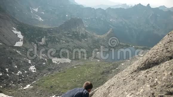 一个勇敢的人在没有保险的情况下爬上悬崖的顶端视频的预览图
