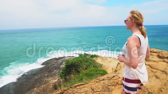 女旅行者站在海边看着海浪美丽的海景视频的预览图