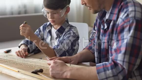 可爱细心的男孩用螺丝刀和木头工作父亲教儿子视频的预览图