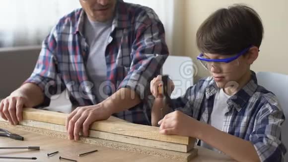 专心致志的小男孩用木板钉钉子父亲支持他的孩子视频的预览图