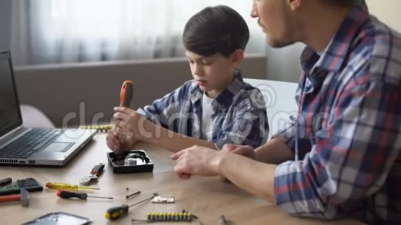 关爱的父亲教他的小儿子在家修理硬盘驱动器爱好视频的预览图