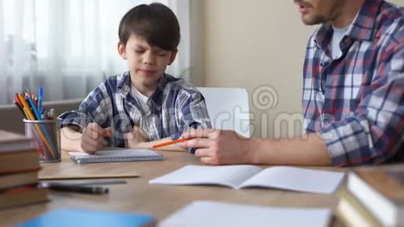 爸爸坐在桌子旁让他任性的儿子做作业教育视频的预览图