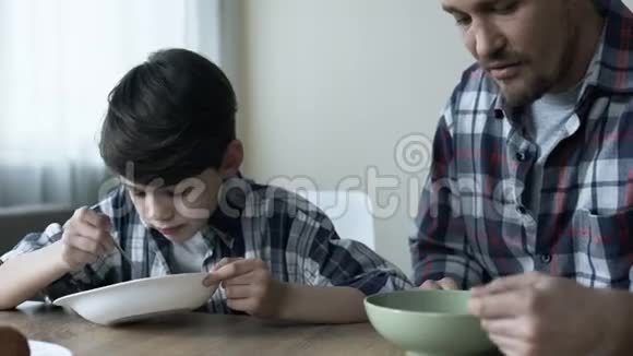 严肃的单身父亲和他的儿子早上吃玉米片糟糕的早餐视频的预览图