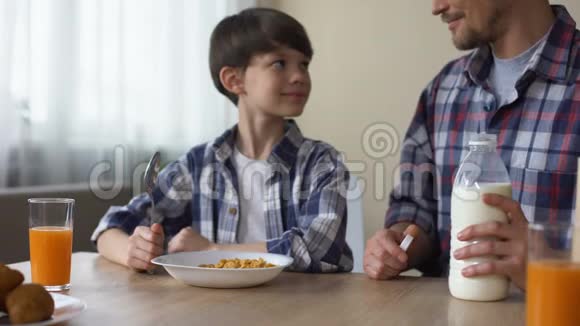父亲用玉米片倒牛奶儿子和爸爸吃早餐视频的预览图