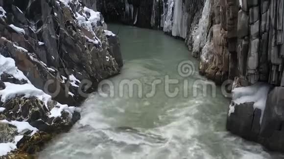 一条高山河流在陡峭的悬崖之间覆盖着冰空中拍摄的画面是4k视频的预览图