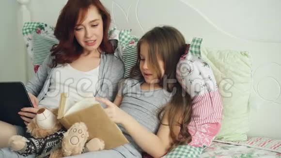 小可爱的女儿和小可爱的妈妈坐着看着有趣的图画一边笑着看童话书视频的预览图