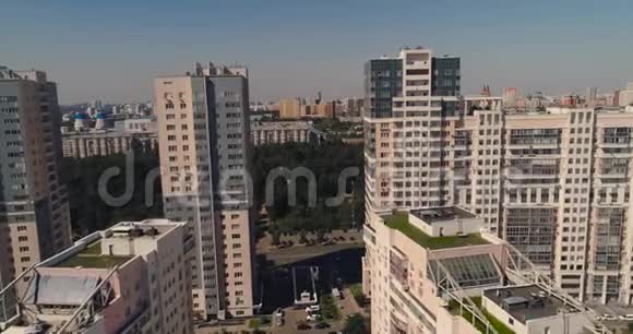 空中无人驾驶飞机在新的现代住宅区和带公园和许多树木的公寓摩天大楼之间飞行视频的预览图