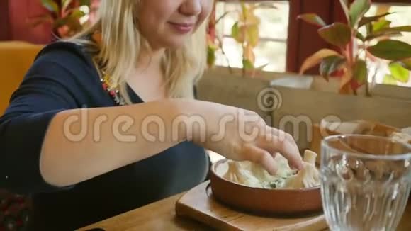 格鲁吉亚菜金发碧眼的人在奶油酱里吃Khinkali慢动作视频的预览图