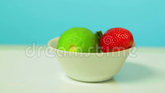 青柠果和成熟的草莓浆果在白色的盘子里旋转成一个圆圈视频的预览图