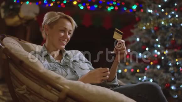 成年女性在圣诞夜使用智能手机和信用卡进行网上购物视频的预览图