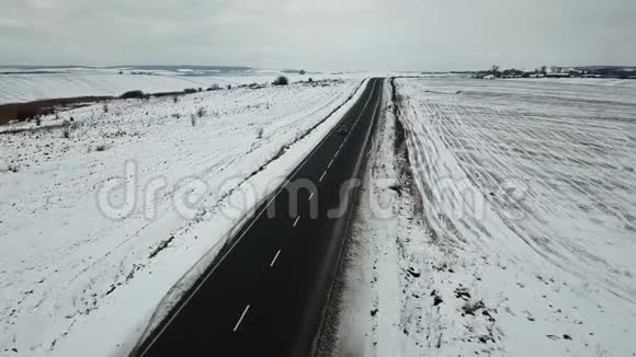鸟瞰冬天道路和白雪覆盖的田野视频的预览图