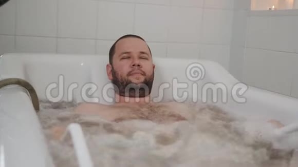 男子在水疗沙龙躺在隐藏按摩浴缸和享受葡萄酒按摩视频的预览图
