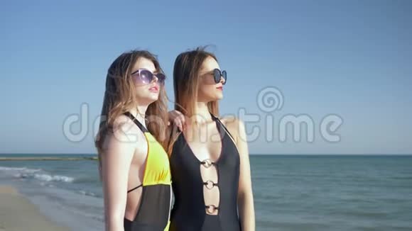 海滩度假穿着泳衣和太阳镜的女朋友看着远方笑着视频的预览图