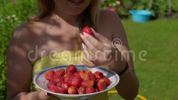 戴着夏帽的女人吃着甜草莓视频的预览图