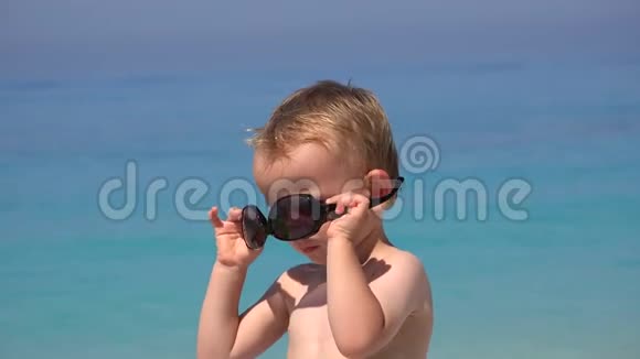 有趣的男孩试图安排太阳镜恼火失败美丽的绿松石海视频的预览图