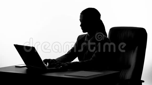 在笔记本电脑上打字的忙碌女人的剪影在工作场所工作的秘书视频的预览图