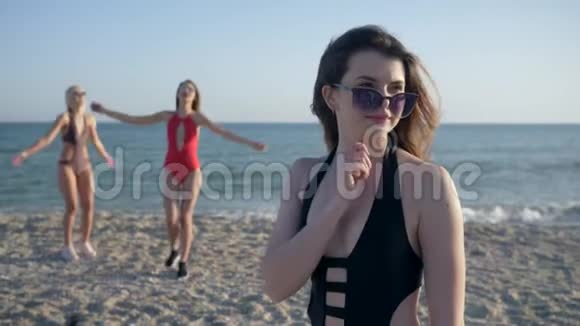 节日快乐戴着墨镜穿着泳装的笑脸女郎在沙滩上以欢快的女友为背景视频的预览图