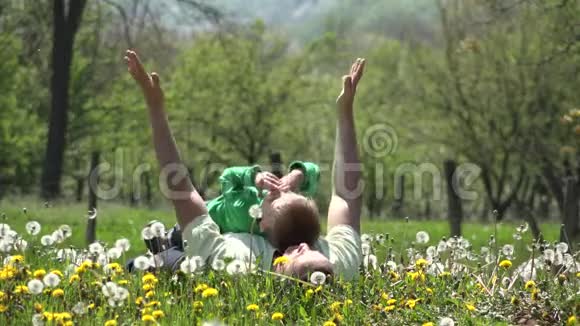 父亲和儿子躺在新鲜的草地上举起手向天空举起视频的预览图