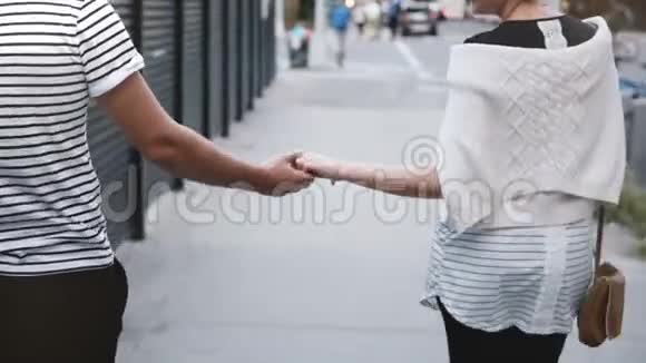 幸福的多民族浪漫情侣走在傍晚索霍纽约一起牵手探索城市街道视频的预览图