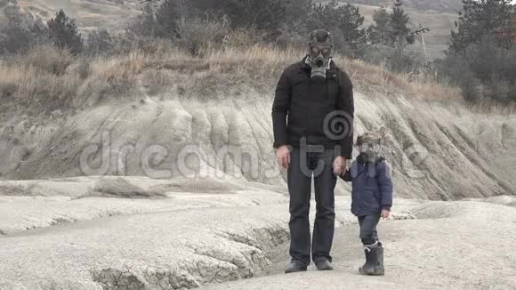 父亲和儿子戴着防毒面具手牵着手在荒凉的地方视频的预览图