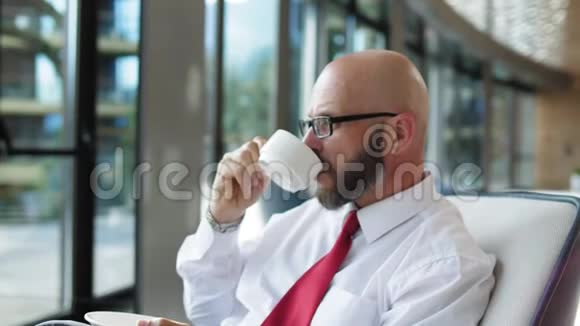 体贴的商人慢吞吞地在机场休息室喝茶视频的预览图