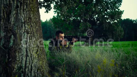 猎人坐在树下瞄准猎物视频的预览图