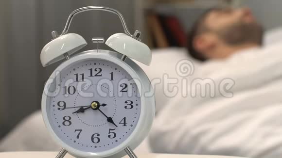 白色闹钟与睡眠男站在床边健康睡眠特写视频的预览图