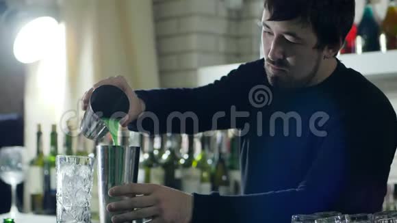 男巴曼将新鲜果汁从金属杯倒入柜台视频的预览图