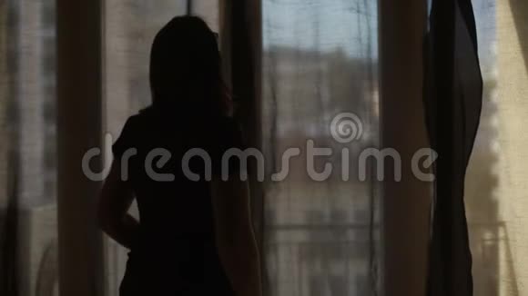 女人拉开窗帘让温暖的夏日阳光照进房间视频的预览图