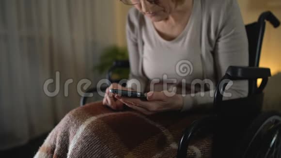 坐轮椅的老妇人在智能手机上看照片对孙子的爱视频的预览图