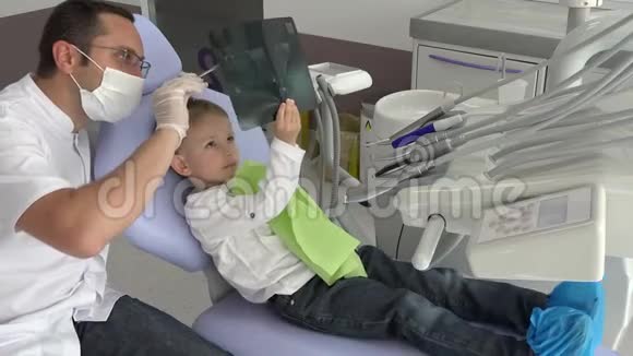 友好的医生向可爱的孩子展示他的牙齿放射线视频的预览图