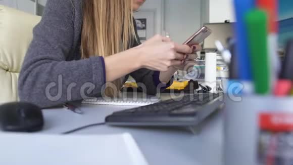 年轻女性在智能手机上滚动在办公室浪费时间在工作中疏忽视频的预览图