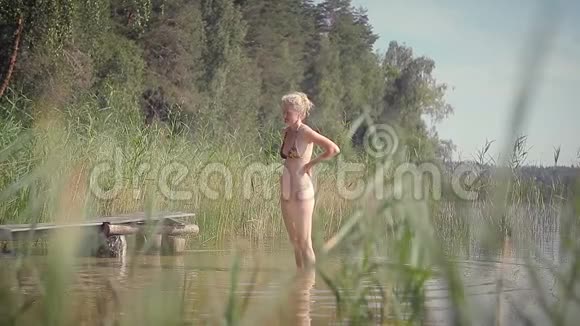 一个迷人的女人站在湖边的水中放松视频的预览图