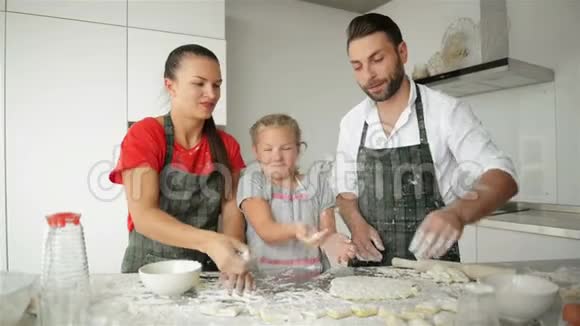 可爱的父母正在教他们的女儿如何烹饪披萨他们相处得很好视频的预览图
