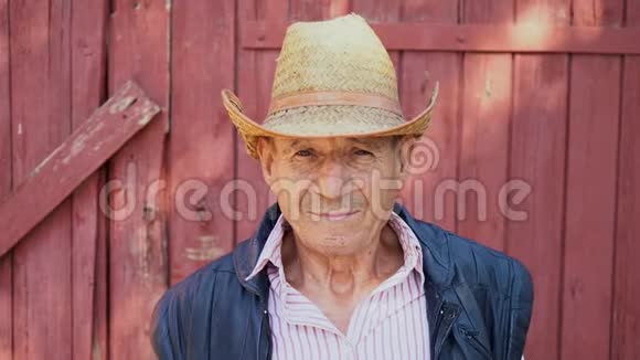 农场背景上戴草帽的一位老年农民的肖像一个年龄的男人的脸视频的预览图