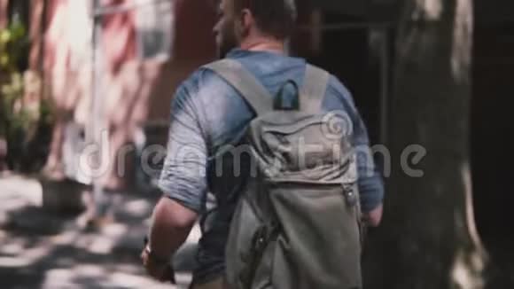 镜头跟随年轻放松的当地男子与背包走在阴凉的夏季布鲁克林街在纽约慢动作视频的预览图