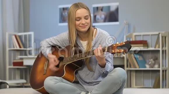 年轻女子在房间里弹吉他写歌梦想着音乐事业视频的预览图